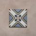 Single tile from the Carnaby Turner Victorian-style collection, 20x20cm porcelain wall and floor tile, featuring a blue, cream, and charcoal geometric cross pattern with small gold accents on an aged background.
