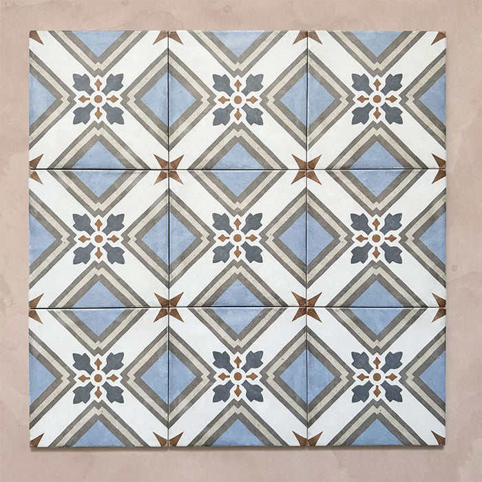 Grouped layout of Carnaby Turner Victorian-style 20x20cm porcelain wall and floor tiles, showing the full repeating blue, cream, and charcoal geometric cross pattern with small gold accents on an aged background.