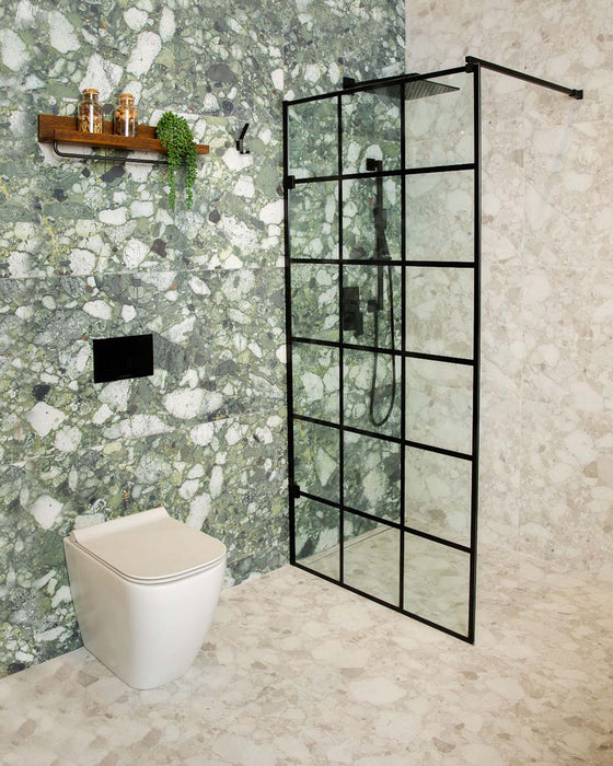 Contemporary bathroom featuring Venetian Ivory 60cm x 60cm terrazzo effect matt porcelain wall and floor tiles, paired with contrasting green terrazzo effect feature walls, black-framed shower screen and minimalist black brassware.