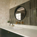 Contemporary bathroom vanity featuring Venetian Ivory terrazzo effect wall tiles, Izmir Sage Green gloss brick splashback tiles, Agraba Natural Moroccan style patterned floor tiles, a dark green floating vanity and brushed brass brassware.