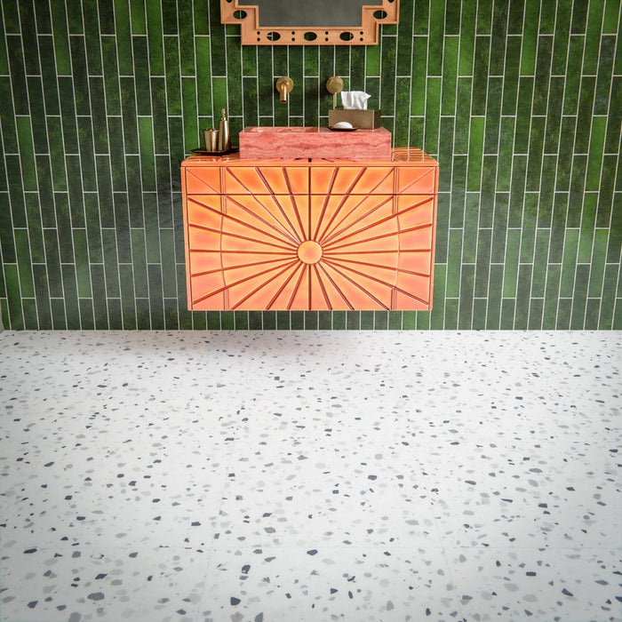 Bathroom interior featuring Veneto Medium White 60 × 60cm terrazzo-effect porcelain floor tiles, showcasing a soft white base with scattered grey stone fragments, paired with Malaga Tourmaline Green gloss brick wall tiles, a statement coral vanity unit, and brushed brass fittings for a bold yet balanced contemporary space.