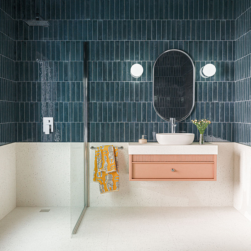 Bathroom featuring Veneto Micro White 60x60cm terrazzo effect porcelain floor tiles, with subtle grey speckled detailing, paired with deep blue vertical wall tiles, a walk-in shower, blush pink vanity unit and chrome fixtures.