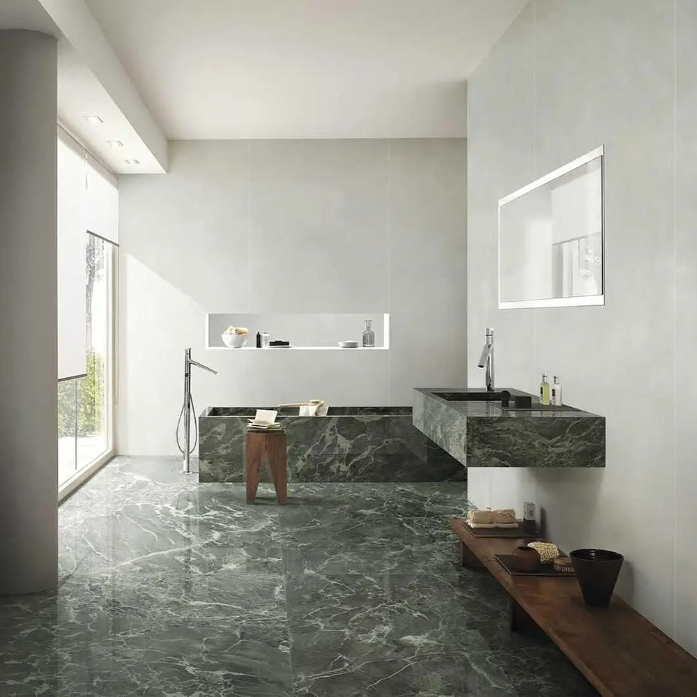 Bathroom interior featuring Grand Verde Apia Matt Green Marble effect 60 × 120cm porcelain wall and floor tiles, styled with a built-in bath, floating vanity, and soft natural light highlighting rich green tones and subtle veining.