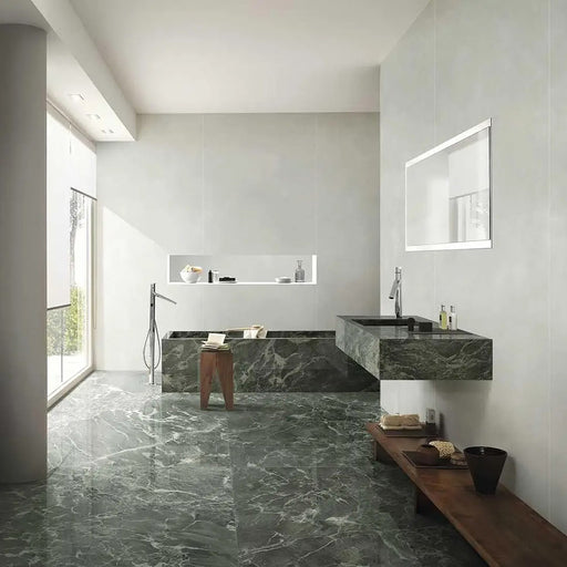 Bathroom interior featuring Grand Verde Apia Matt Green Marble effect 60 × 120cm porcelain wall and floor tiles, styled with a built-in bath, floating vanity, and soft natural light highlighting rich green tones and subtle veining.