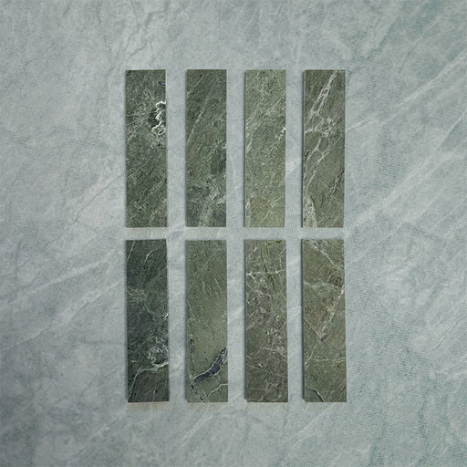 Eight Fitzrovia Verde 5 x 20cm honed natural marble tiles arranged on a soft neutral backdrop, showcasing rich green tones with subtle natural veining and variation, highlighting the depth and character of the stone.
