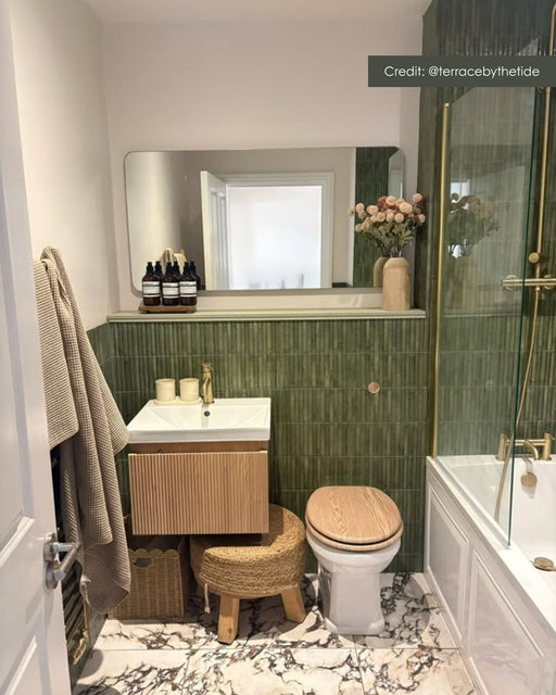Contemporary bathroom featuring Grand Violetta matt marble effect porcelain floor tiles in 60cm x 60cm. Large-format marble effect flooring complements deep green fluted wall tiles, warm wood furniture and brushed brass fittings for a sophisticated modern look.