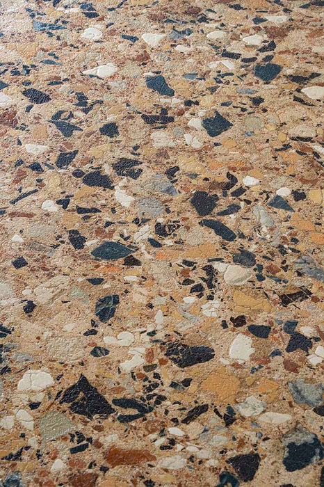 Close-up of the Vito Umbar 60x120cm terrazzo style porcelain tile, highlighting its rich amber-brown base with a blend of ochre, cream, rust, charcoal and soft grey stone fragments. The realistic 4D brushed finish enhances the texture and depth, creating an authentic terrazzo effect.