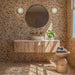 Bathroom featuring Vito Umbar 60cm x 60cm terrazzo style tiles across the walls and floor, showcasing a rich warm-toned terrazzo design with multicoloured stone details, paired with a textured wood vanity, brass fixtures and natural accessories.