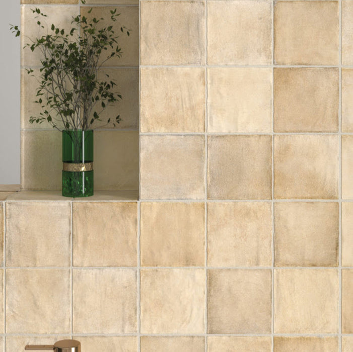 Zellij Arena Square Moroccan Style 10cm x 10cm wall setting, square Moroccan tiles in warm sandy beige and soft golden tones, subtle tonal variation with gently rippled glazed finish, handcrafted-style surface texture, installed on a feature wall for a warm, earthy interior look.