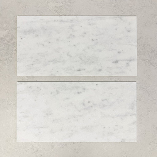 Close-up of Fitzrovia White natural marble tiles in a honed finish, 30.5x61cm format, showcasing a soft white base with gentle grey veining and subtle tonal variation, creating a timeless and refined look for wall and floor applications.