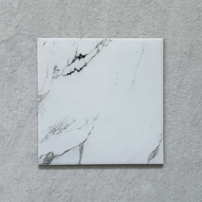 Calacatta Blanca White marble-effect 25×25cm porcelain tile featuring a soft white base with subtle grey veining, designed for elegant floors and walls in modern and classic interiors.