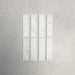 Group of Fitzrovia White 5x20cm honed natural marble brick tiles arranged in a neat layout, showcasing soft white tones, subtle grey veining, and a smooth, refined finish ideal for wall installations.