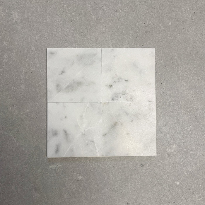 Fitzrovia White 15.2x15.2cm honed natural marble tiles arranged in a square layout, showcasing soft white tones, subtle grey veining, tonal variation, and a smooth, refined finish.