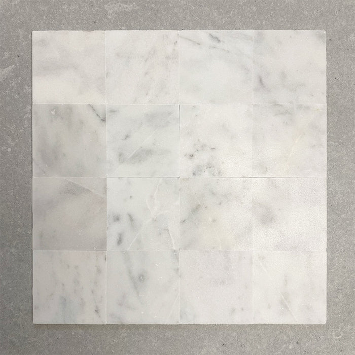Group of Fitzrovia White 15.2x15.2cm honed natural marble tiles arranged in a square layout, showcasing soft white tones, subtle grey veining, tonal variation, and a smooth, refined finish.
