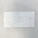 Fitzrovia White 30.5x61cm natural marble tiles with a honed finish, featuring soft white tones with delicate grey veining, shown as a single tile sample laid horizontally against a light textured backdrop.