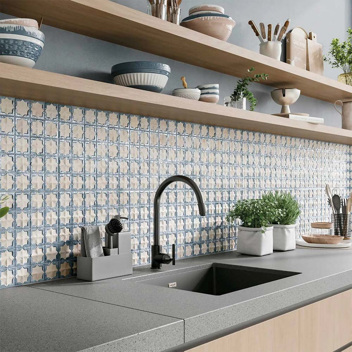 Contemporary kitchen featuring Zeina Moroccan Arena Blue ceramic wall tiles as a Moroccan style splashback, paired with floating oak shelves, pale wood cabinetry, grey worktops, a black tap and sink, and soft blue walls for a calm, modern finish.