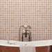 Bathroom featuring Zeina Moroccan Cotto White ceramic wall tiles in a repeating Moroccan style geometric pattern, paired with a freestanding copper bath, terracotta effect floor tiles, arched window, woven pendant light and olive trees for a warm Mediterranean-inspired retreat.