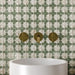 Bathroom vanity featuring Zeina Moroccan Emerald Green ceramic wall tiles in a repeating Moroccan style geometric pattern, paired with a round white basin, brushed brass wall-mounted taps and contemporary styling to create a timeless Mediterranean-inspired bathroom.