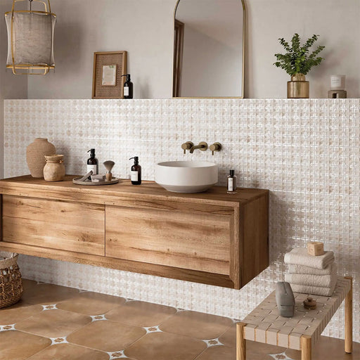 Bathroom featuring Zeina Moroccan Natural White ceramic wall tiles in a repeating Moroccan style geometric pattern, paired with a floating oak vanity, brushed brass wall-mounted taps, warm stone effect floor tiles, neutral décor and natural textures for a calm Mediterranean-inspired space.