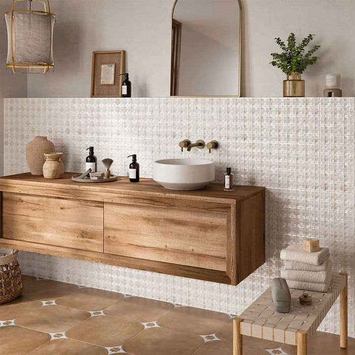 Bathroom featuring Zeina Moroccan Natural White ceramic wall tiles in a repeating Moroccan style geometric pattern, paired with a floating oak vanity, brushed brass wall-mounted taps, warm stone effect floor tiles, neutral décor and natural textures for a calm Mediterranean-inspired space.