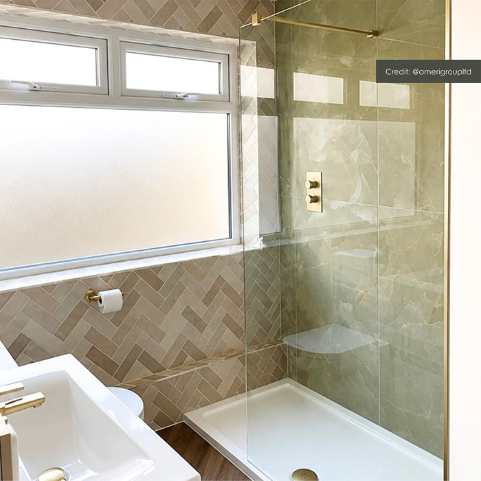 Bathroom featuring Zellij Bone Brick 6.5x20cm Moroccan-style wall tiles, arranged in a herringbone pattern in soft beige tones, paired with green marble-effect shower tiles, a glass shower screen and brushed brass fixtures.
