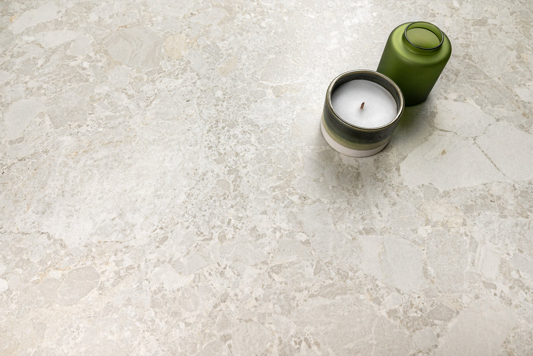 Contract Pebble Rock Blanca porcelain tile 60x120 with soft stone fragments and pale ivory-grey tones, close-up surface detail