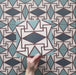 Video showcasing the Geometry Iris 20x20cm patterned tile, highlighting its intricate teal, navy, terracotta-red, and cream geometric design, and demonstrating how the pattern connects and repeats when multiple tiles are laid together.