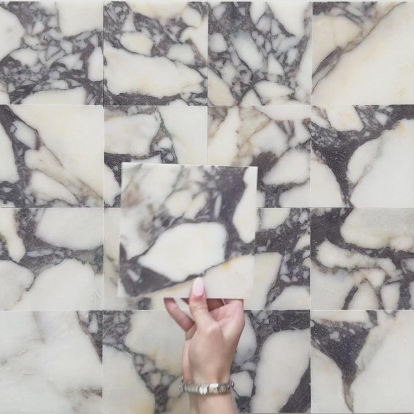 Video of Fitzrovia Calacatta Viola honed natural marble tile in a 15.2cm x 15.2cm square format, featuring a creamy white background with bold purple veining and subtle warm gold tones, creating a luxurious and timeless natural stone finish.