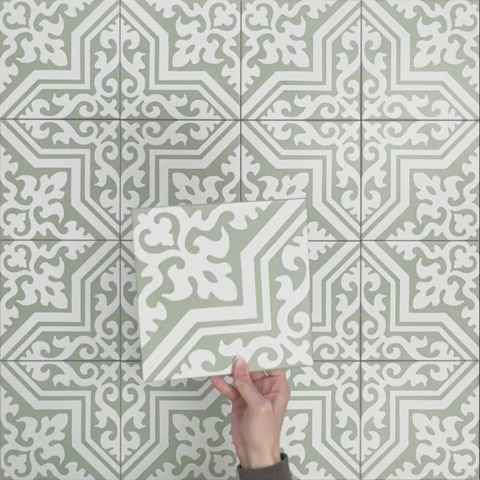 Video showcasing Europa Trondheim Sage Green 20x20cm Victorian Moroccan style tiles arranged together to showcase the repeating decorative pattern in sage green and white tones, displayed against a textured green background.