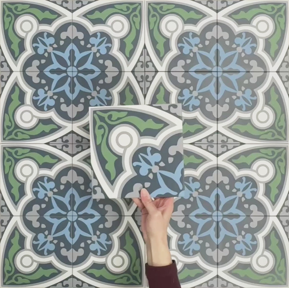 Video showcasing Europa Bucharest 20x20cm Victorian Moroccan style tiles arranged together to showcase the repeating ornamental pattern in blue, green, grey and white tones, displayed against a textured blue background.