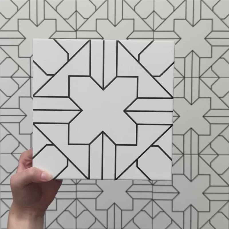 Video showcasing the Alhambra Palacio 20x20cm Moroccan tile, featuring a striking black geometric cross pattern on a white background, highlighting its intricate design and smooth matte finish.
