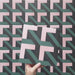 Video showcasing the Geometry Lagoon 20x20cm patterned tile, highlighting its interlocking geometric design in blush pink, deep teal, and charcoal tones, and demonstrating how the pattern connects seamlessly when multiple tiles are laid together.