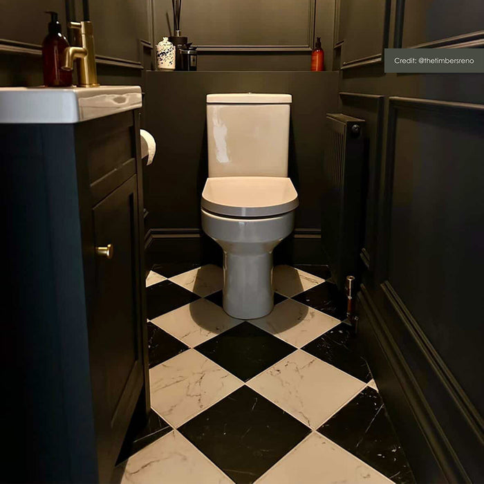 Calacatta Blanca White 25x25cm marble effect porcelain tiles laid in a classic black and white chequerboard pattern, creating a bold statement floor in a compact cloakroom with dark panelled walls and brushed brass fittings.